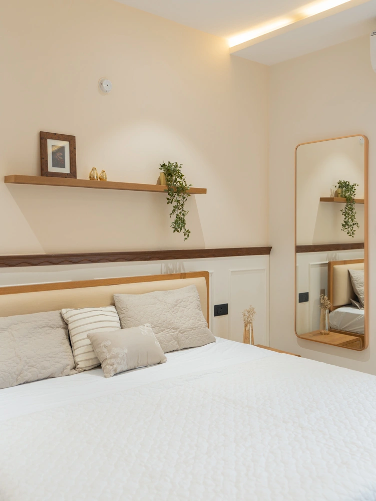 A softly lit bedroom with pale timber, a bedside pendant and an open wall shelf