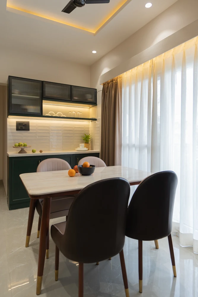 A dining table with curved chairs beside a full-height curtain and open shelving