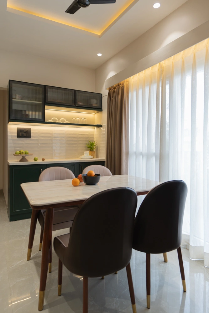 A dining table with curved chairs beside a full-height curtain and open shelving